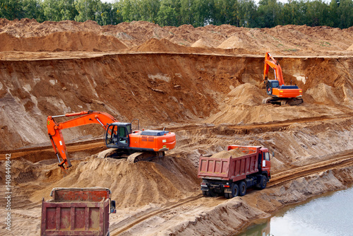 The process of loading sand into trucks at a quarry is a mining operation. Excavators and heavy trucks are involved in this process