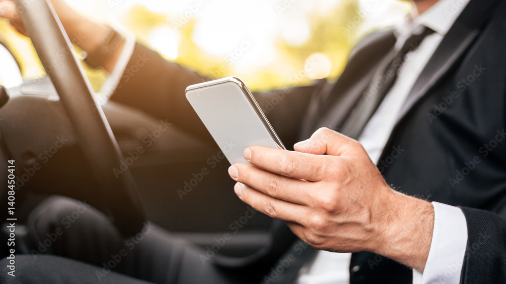 Obraz premium Driving safety concept. Cropped of businessman driving car, using mobile phone, checking location of business meeting, side view, copy space. Unrecognizable man using smartphone while driving