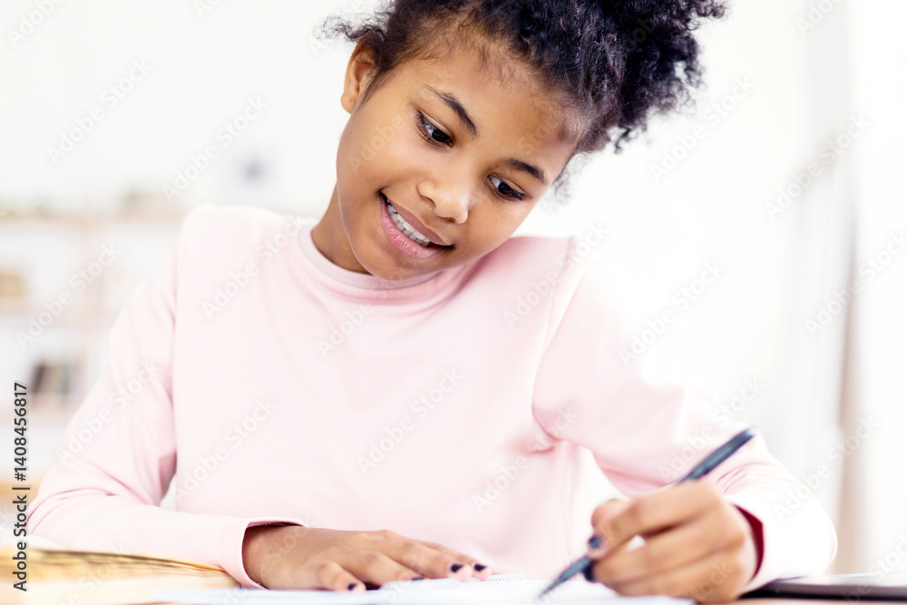 African Teen Girl Doing Homework Writing In Exercise-Book Sitting At Desk At Home. Selective Focus African Teen Girl Doing Homework Writing In Exercise-Book Sitting At Desk At Home. Selective Focus