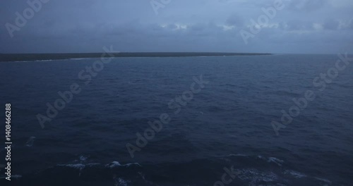 Video of gloomy overcast day from boat overlooking call water small sliver of land on the horizon.
