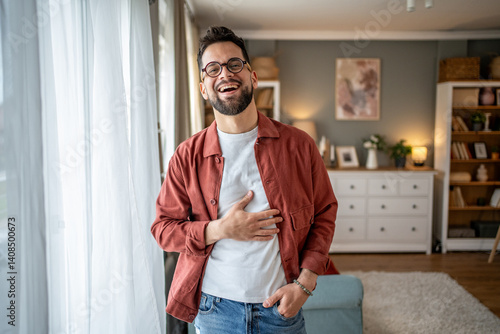 Foto Cheerful man laughing holding his stomach at home