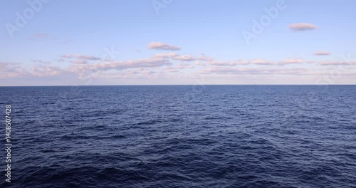 4k Video captured from deck of cruise ship overlooking a vast calm deep blue wide open ocean with light fluffy clouds