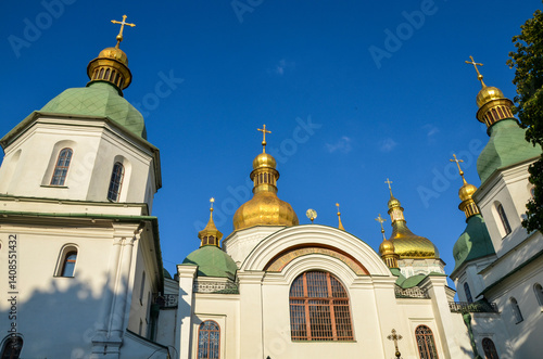 Exterior of Saint Sophia s Cathedral in Kyiv  Ukraine  under a clear blue sky. The cathedral features white walls  green roofs  and golden domes with crosses