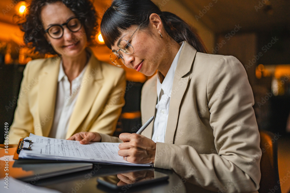 Fototapeta premium caucasian businesswoman give to japanese female client contract to sign