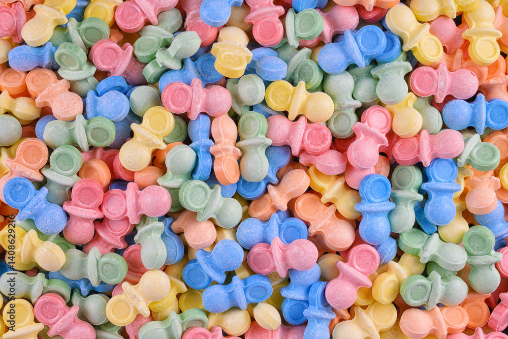 Colorful pacifier-shaped candy in pastel hues creates a playful, sweet background. Ideal for baby shower themes, childhood nostalgia, candy promotions, or confectionery product design.
