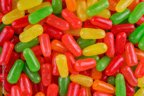 Obraz na płótnie Vibrant assortment of colorful jelly bean-shaped candy in red, yellow, green, and orange tones. w salonie