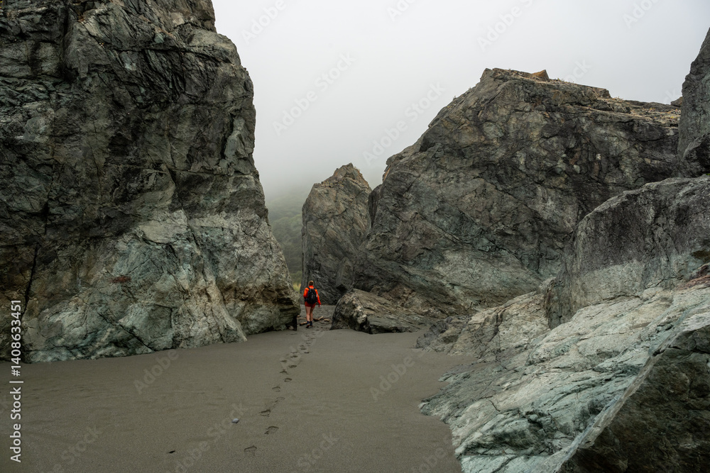 Hiker Walks Through The Exposed Rocks at Low Tide On The Coastal Trail In Redwood
