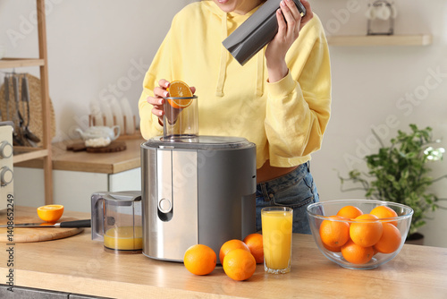 Young woman making orange j...