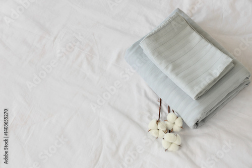 Obraz na płótnie Stack of grey linen with cotton flowers on bed, top view w salonie