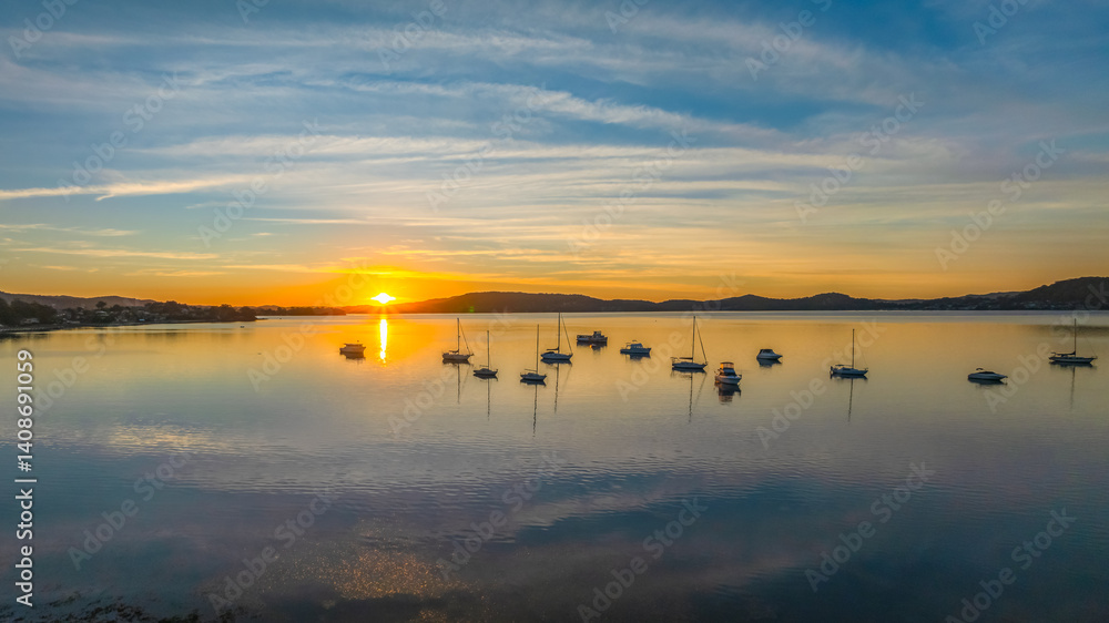 Sunrise with high cloud, boats and reflections over the water Sunrise with high cloud, boats and reflections over the water