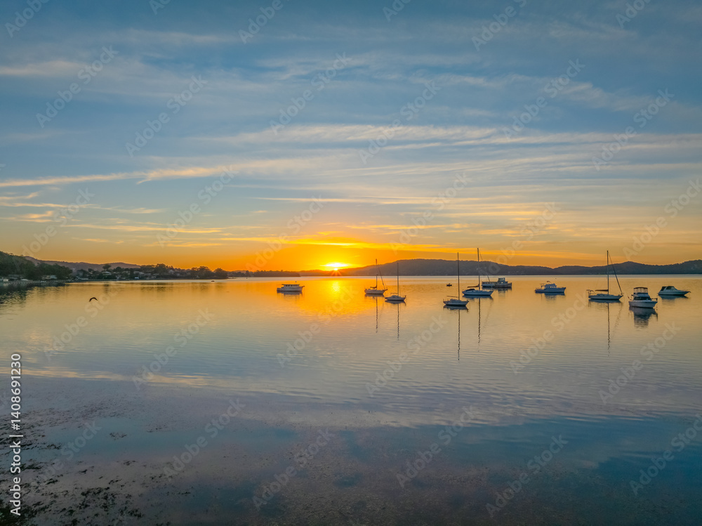 Fototapeta premium Sunrise with high cloud, boats and reflections over the water