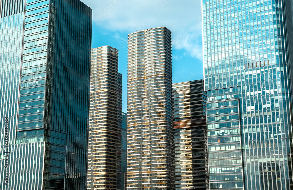 Fototapeta premium Modern skyscrapers reflect sunlight against a clear blue sky in an urban landscape in a bustling city