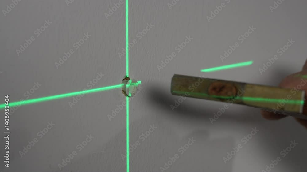 Construction worker hammers a plastic dowel into a drilled hole in a wall and then tightens the screw with a screwdriver, close up. The center of the hole is marked with green lines of the laser level Construction worker hammers a plastic dowel into a drilled hole in a wall and then tightens the screw with a screwdriver, close up. The center of the hole is marked with green lines of the laser level