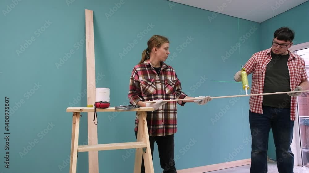 couple renovating new house apartment decorating wall together using laser level. Home makeover, renovation concept. Family man woman repair flat themselves. couple renovating new house apartment decorating wall together using laser level. Home makeover, renovation concept. Family man woman repair flat themselves.