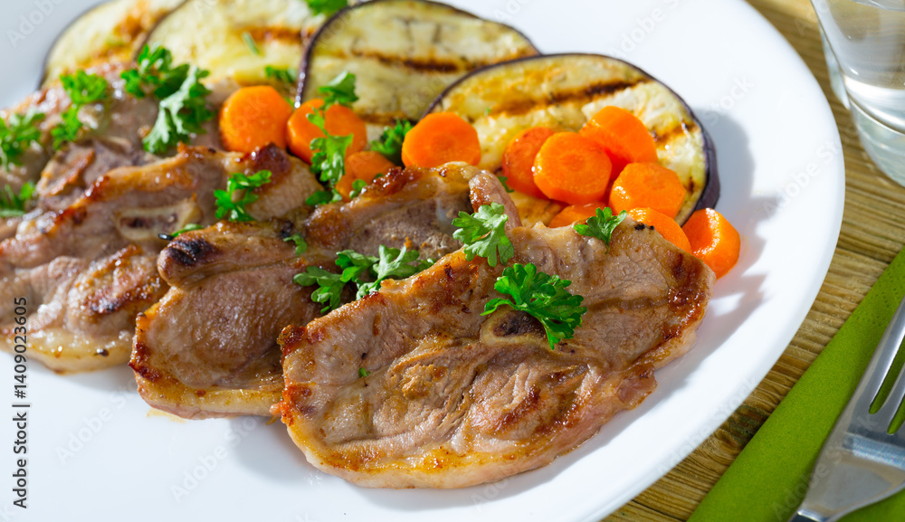Tasty mutton loin chops grilled with eggplant slices and carrots garnished with fresh parsley Tasty mutton loin chops grilled with eggplant slices and carrots garnished with fresh parsley