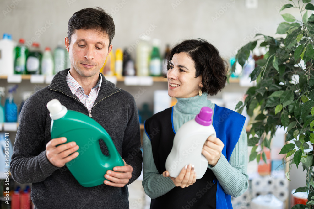 Adult woman seller offers laundry detergent to adult man buyer in household chemicals store