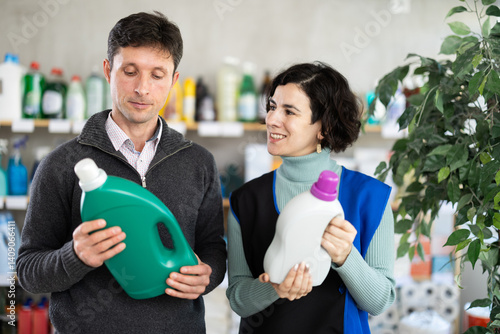 Obraz na płótnie Adult woman seller offers laundry detergent to adult man buyer in household chemicals store w salonie