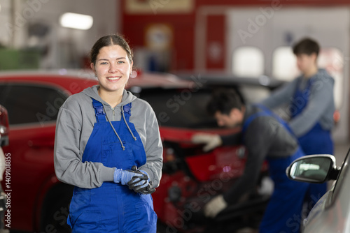 Obraz na płótnie Girl employee performs repairs to external parts of car body and internal components of vehicle. Worker is busy restoring car after damage w salonie