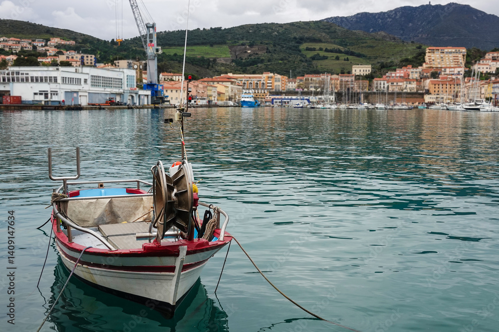 A fishing boat rests peacefully in tranquil water, reflecting the colorful buildings of a coastal town.