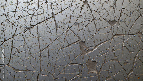Scratched and scored metal surface, exhibiting a network of fine, interlacing abrasions alongside deeper gouges and impacts