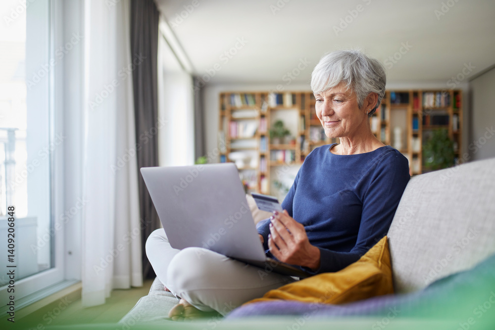 Senior woman shopping online at home using a laptop and credit card Senior woman shopping online at home using a laptop and credit card