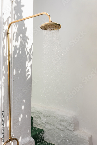 Modern gold outdoor shower with dappled sunlight