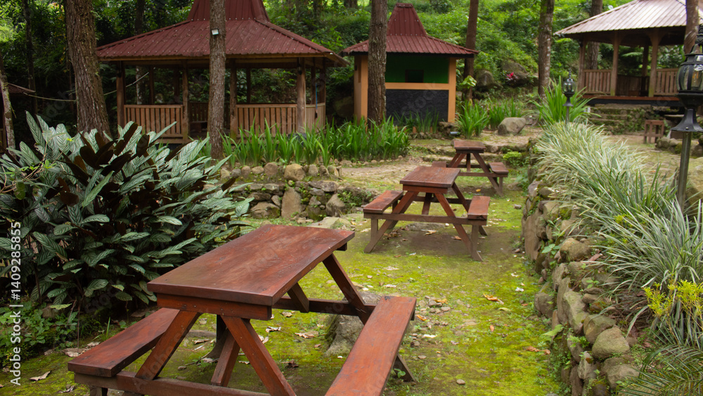 Obraz premium Outdoor Wooden Table and Chairs Set for 4 People, Designed as a Single Piece, Surrounded by Greenery