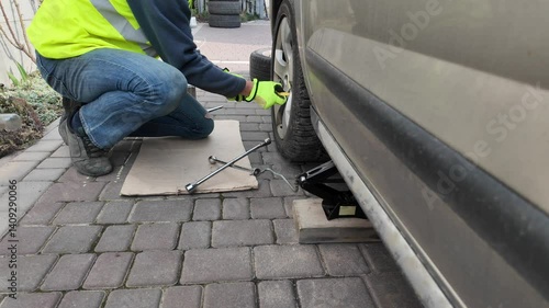 A guy changes tire on street to summer tire in nature