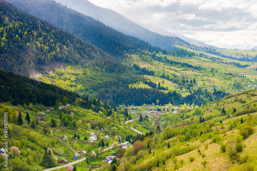 Obraz na płótnie mountainous countryside landscape with synevyr village in the valley. scenic farmland. cloudy weather. rural fields and meadows on the forested slopes of hill. rolling scenery in spring. lush woodland w salonie