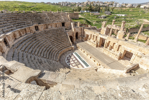 Fotografi Stone seating and stage of jerash roman theatre with modern city in background