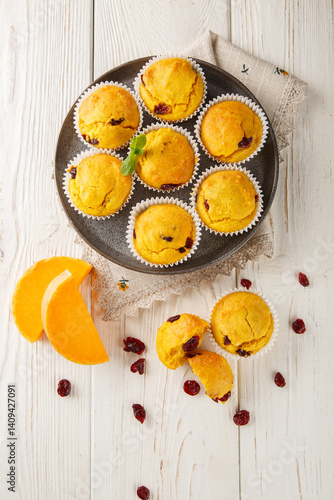 Obraz na płótnie Tender muffins with pumpkin puree and cranberries close-up in a plate on the table. Vertical top view from above w salonie