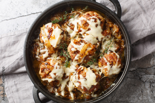 Baked French Onion Meatballs with caramelized onions and Gruyere cheese closeup on the pan on the table. Horizontal top view from above