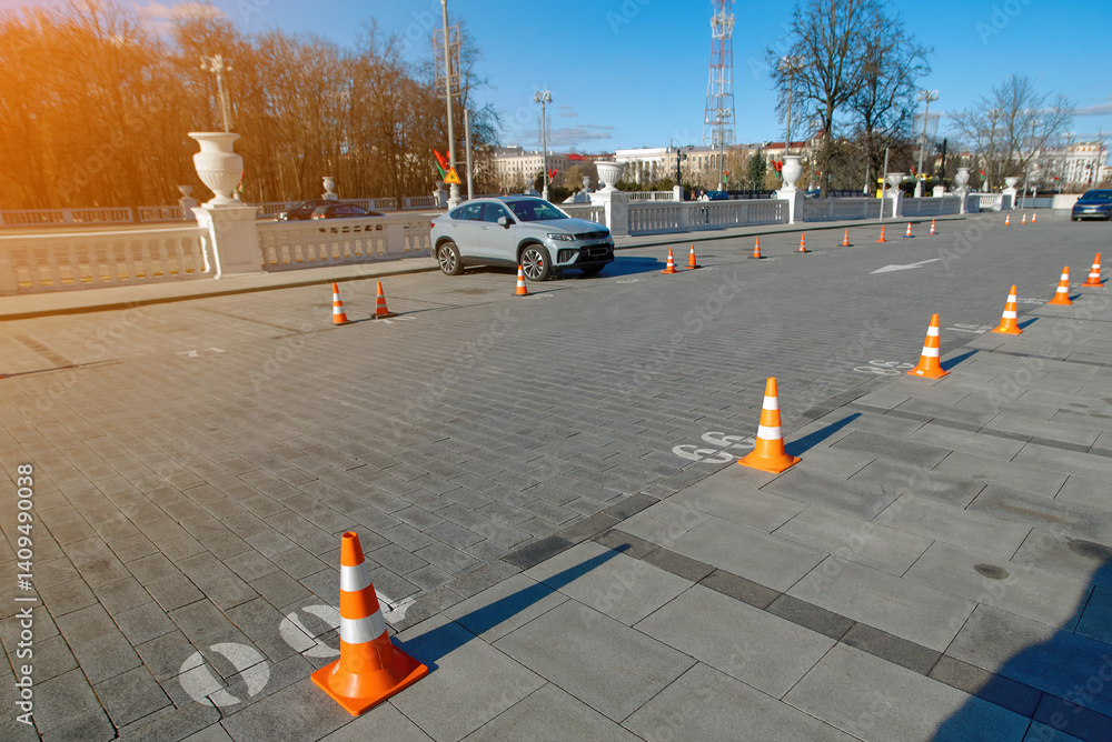 Cones arranged in row to designate and secure parking spots. Organized row of plastic traffic cones used for reserving parking spots, lane control and pedestrian guidance on paved area