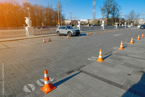 Obraz na płótnie Cones arranged in row to designate and secure parking spots. Organized row of plastic traffic cones used for reserving parking spots, lane control and pedestrian guidance on paved area w salonie
