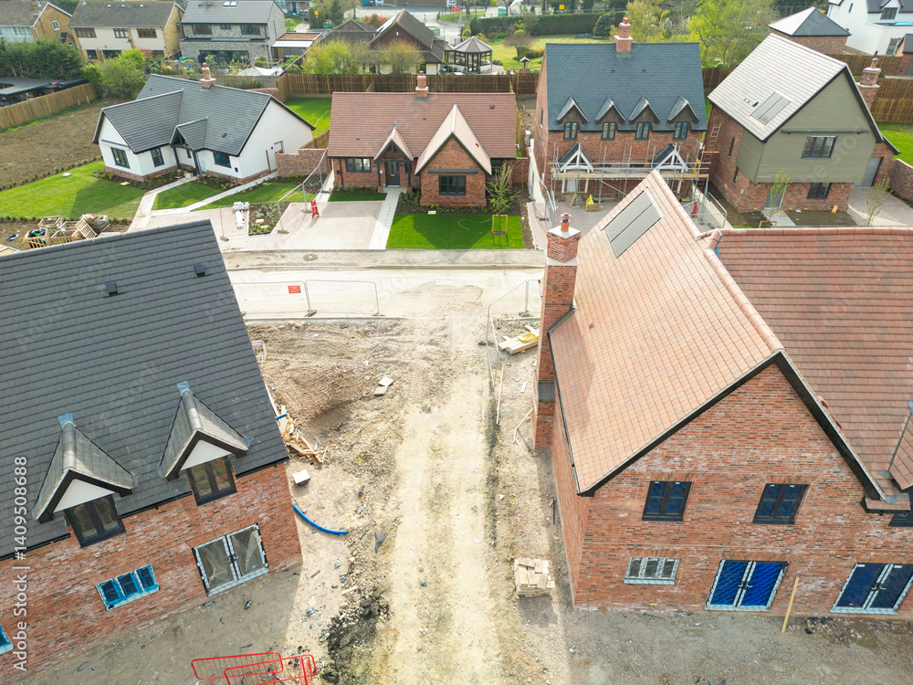 Aerial view of near completed affordable and private homes on a rural housing development in the east of England. The distance shows private bungalows.