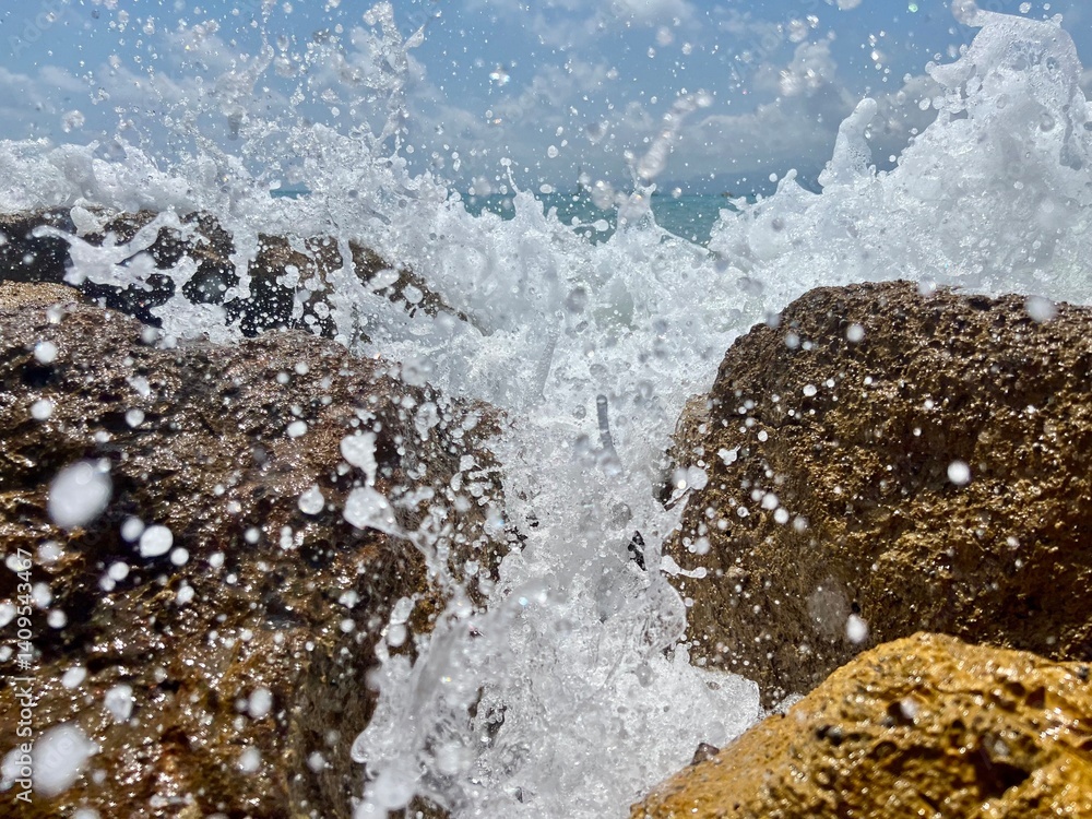 Obraz premium Ocean waves crashing against rocks on sunny day