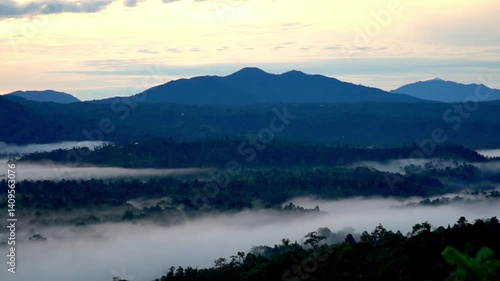 Wallpaper Mural Sunrise over Bukit Gerdai in Liwa, West Lampung, Indonesia, where thick mist blankets the hills, creating a dreamy tropical view with warm light and natural serenity. Torontodigital.ca
