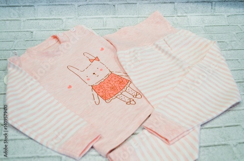 Cute pink pajamas with bunny print for kids on brick background