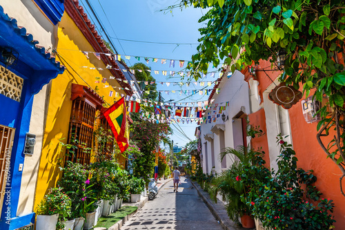 A view down a brightly coloured, flower decorated backstreet in the Getsemani district of Cartagena, Columbia in springtime