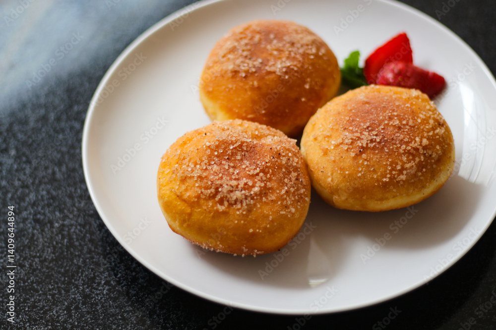 A handmade bombolone or bomboloni is an Italian-filled doughnut that is eaten as a snack or dessert. Selective focus. A handmade bombolone or bomboloni is an Italian-filled doughnut that is eaten as a snack or dessert. Selective focus.