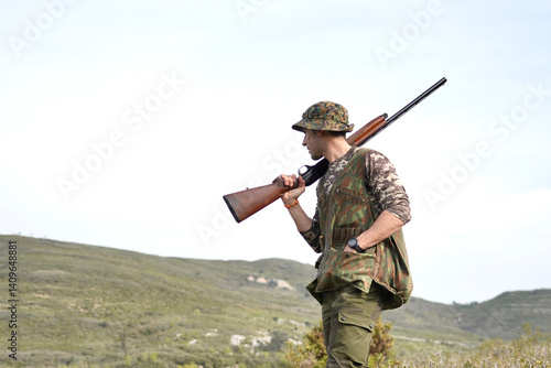 A man in camouflage is holding a shotgun