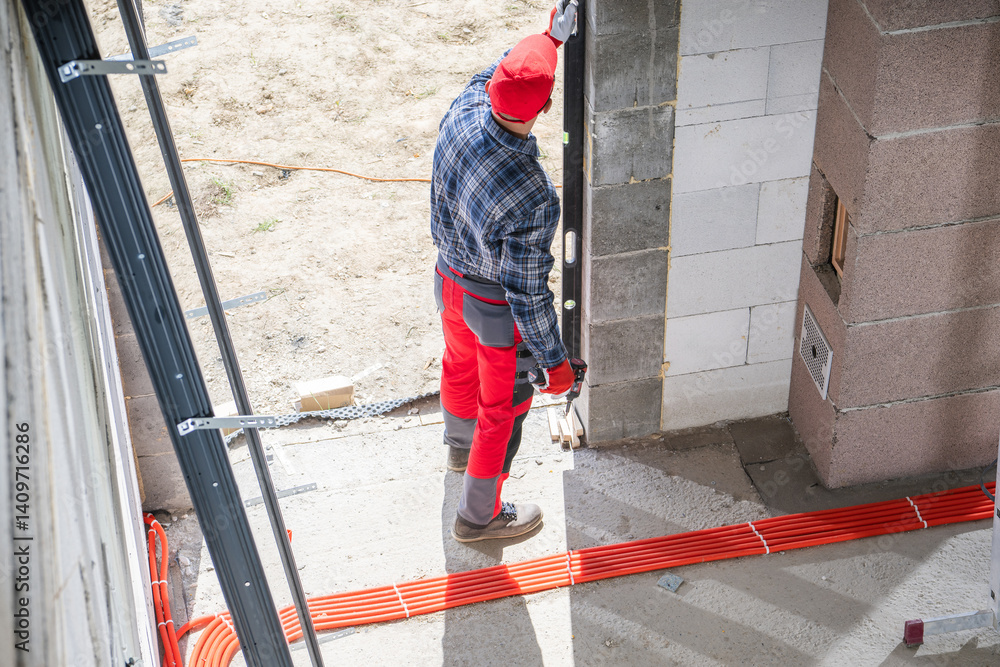 Construction Worker Installs Door at Building Site During Daylight
