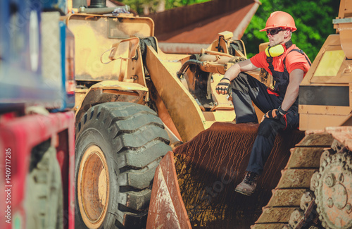 Obraz na płótnie Construction Worker Resting on Heavy Machinery During Work Hours w salonie