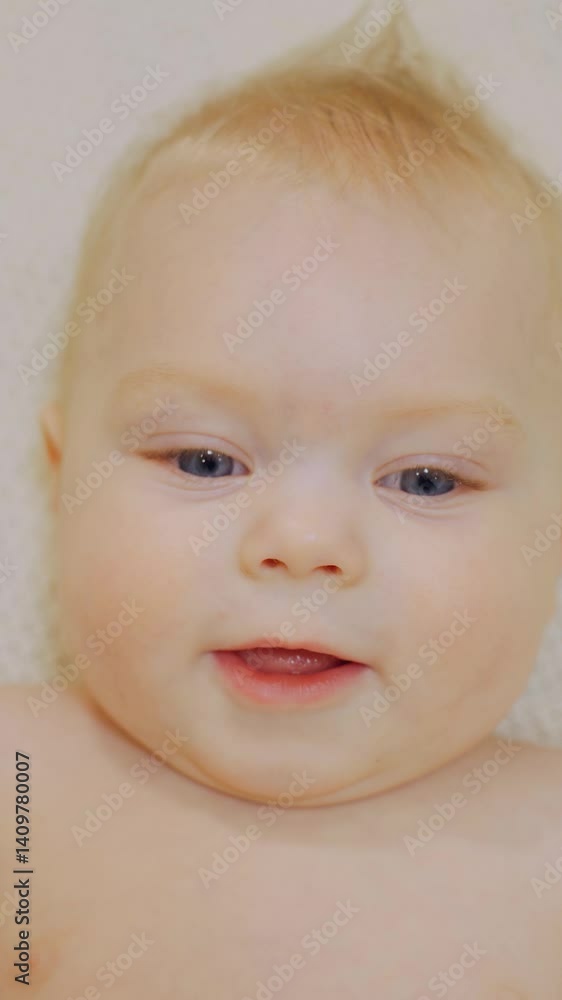 Portrait of a Caucasian white newborn. Beautiful charming positive healthy baby boy, close-up. Face blond baby with blue eyes, the infant lies on his back, smiles. Vertical video. Portrait of a Caucasian white newborn. Beautiful charming positive healthy baby boy, close-up. Face blond baby with blue eyes, the infant lies on his back, smiles. Vertical video.