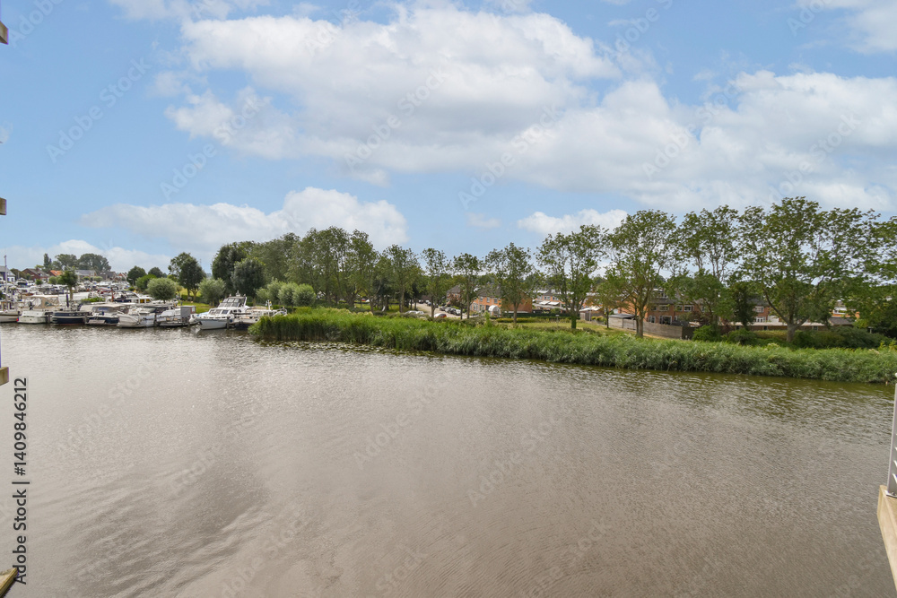 A tranquil river scene showcasing a variety of boats moored alongside lush greenery and a serene waterfront lined with trees. A tranquil river scene showcasing a variety of boats moored alongside lush greenery and a serene waterfront lined with trees.