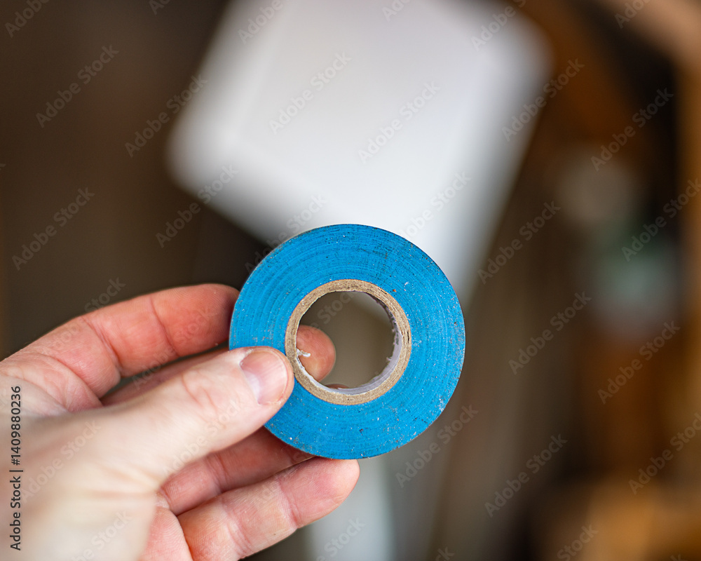 Electrical blue tape roll, holding hand equipment handyman.