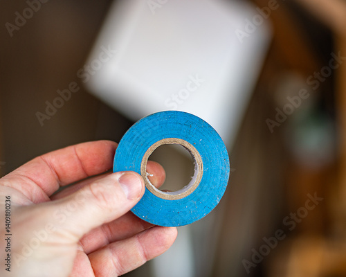 Obraz na płótnie Electrical blue tape roll, holding hand equipment handyman. w salonie