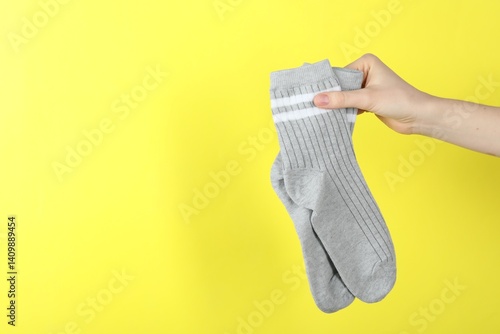 Obraz na płótnie Woman with pair of socks on yellow background, closeup. Space for text w salonie