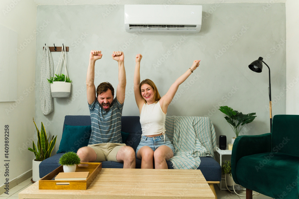 Good looking young couple celebrating cool air conditioning at home
