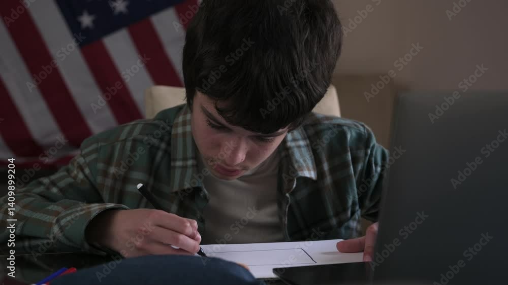 Teenage Boy Draws American Flag While Using Laptop With Flag in Background Teenage Boy Draws American Flag While Using Laptop With Flag in Background